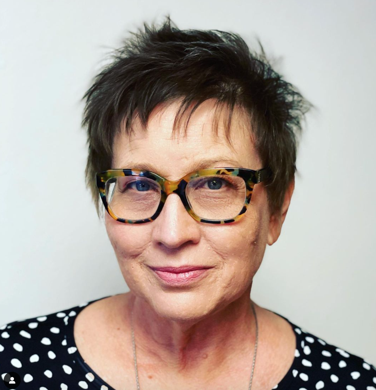 A smiling woman wearing glasses with a short haircut. 