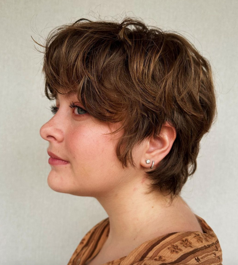 A woman with short wavy brown hair and double-pierced earrings.