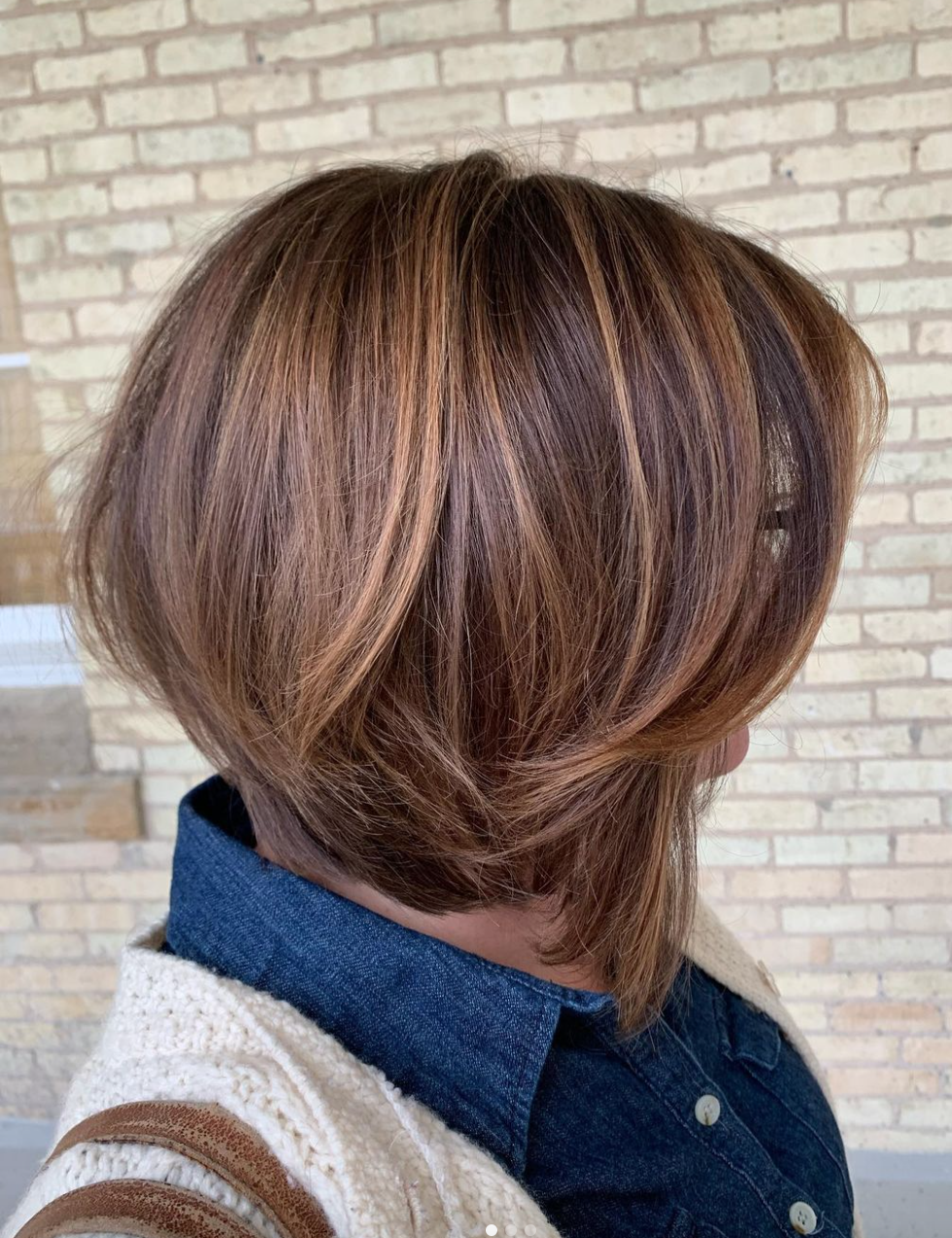 A short haircut on a woman with brown highlighted hair.