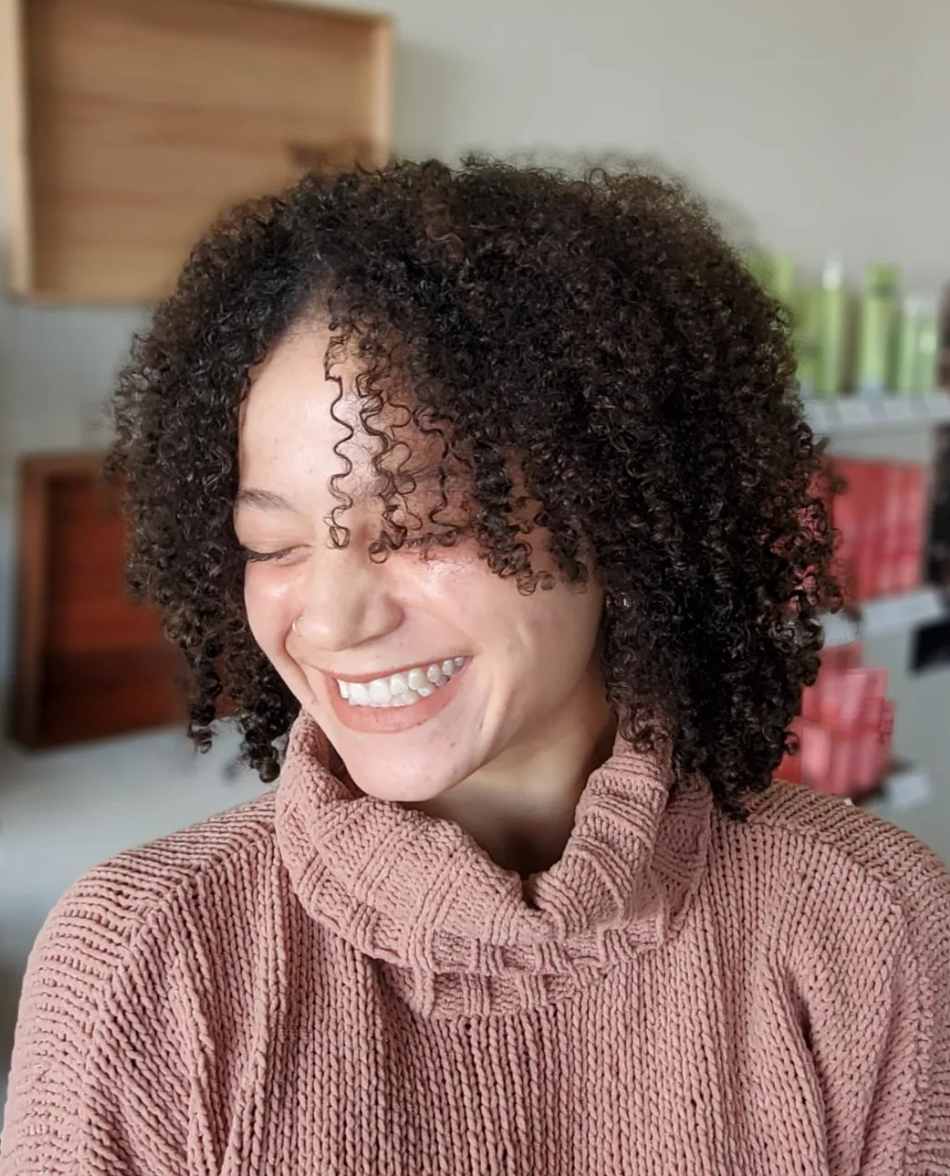 A smiling woman with curly black hair.