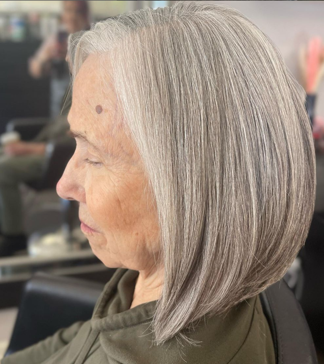 The side profile of a woman with a gray bob haircut.