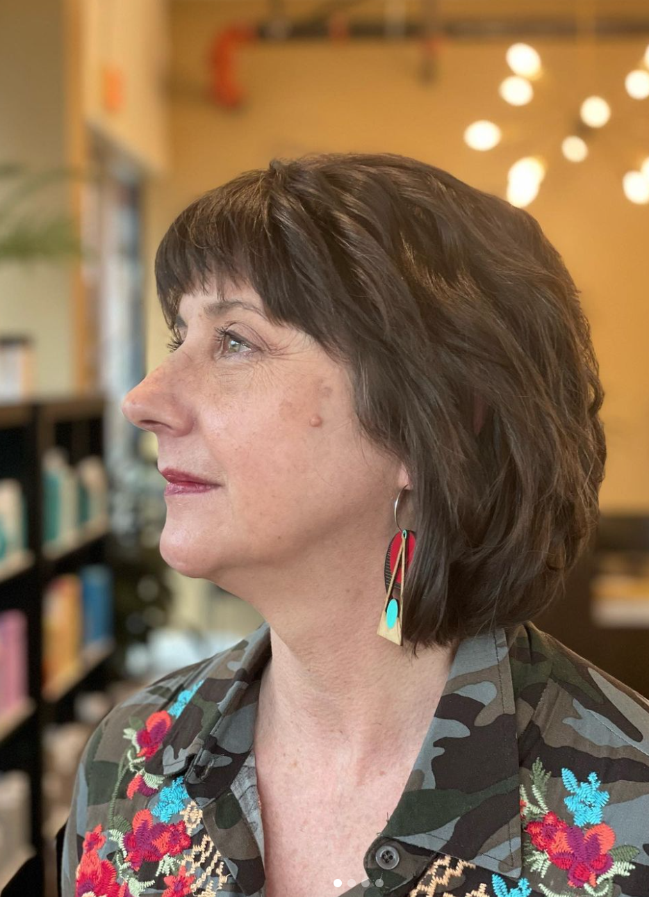 A woman with long colorful earrings looking up.