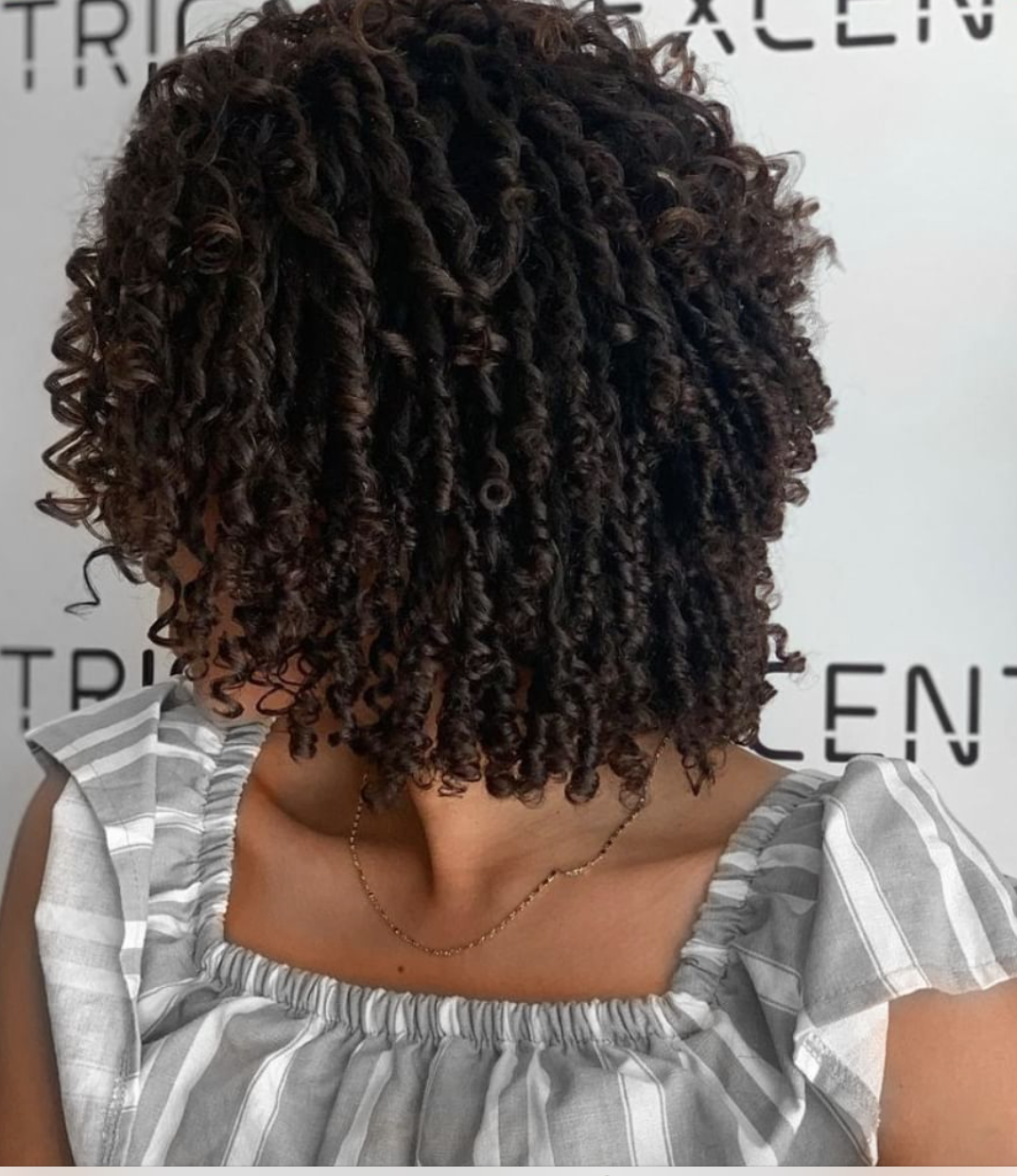 The side view of a woman with curly short black hair.