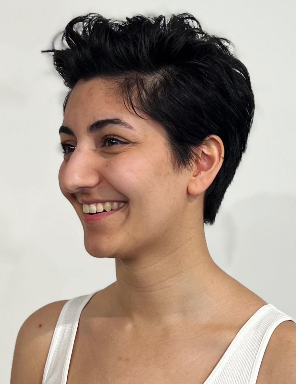 A smiling woman with short black hair looks off to the side. 