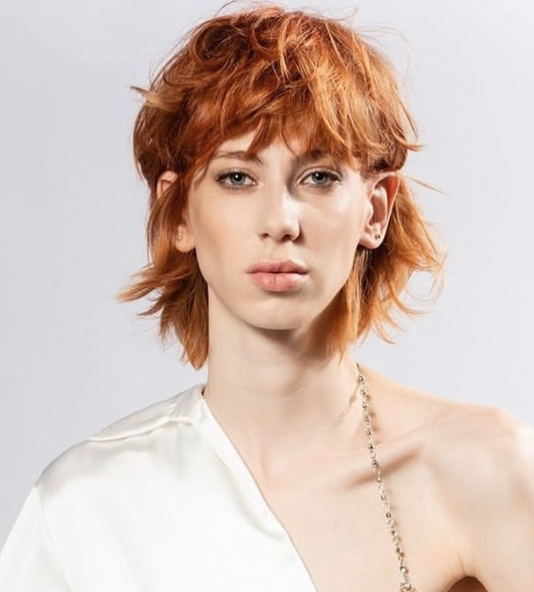 A thin woman with a short haircut on her red hair.