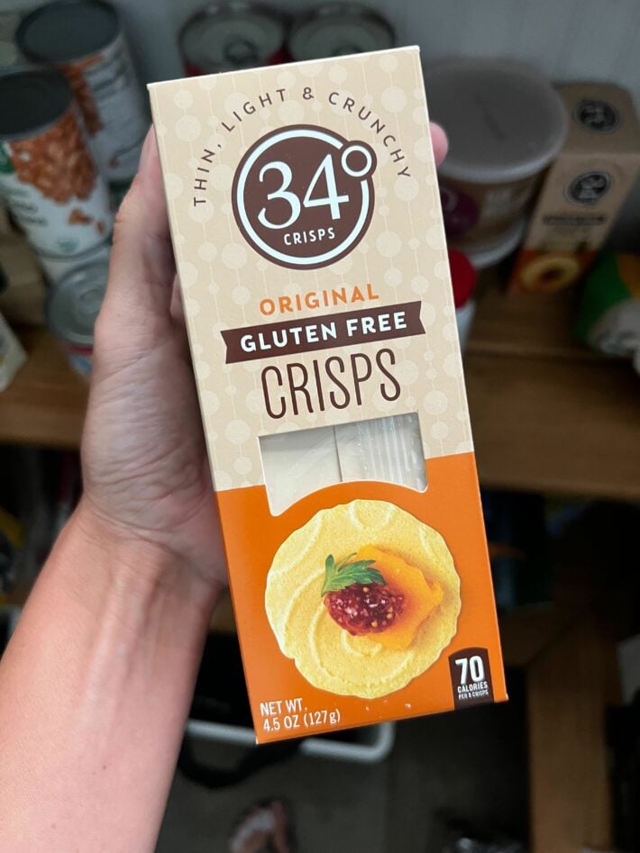 A hand holding up a package of gluten free crisps.