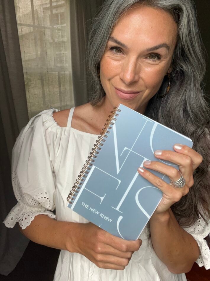 A woman holds up a graduation notebook from Minted. 
