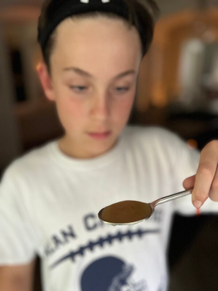 A boy holds up MaryRuth Organics liquid vitamins on a spoon.