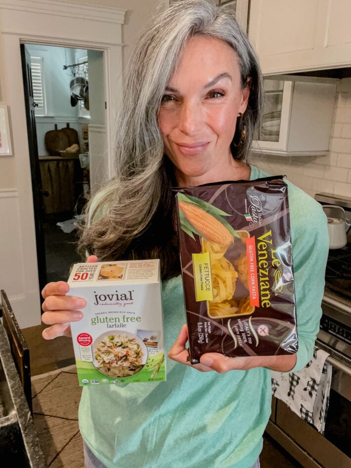 A woman holding up two packages of gluten free pastas.