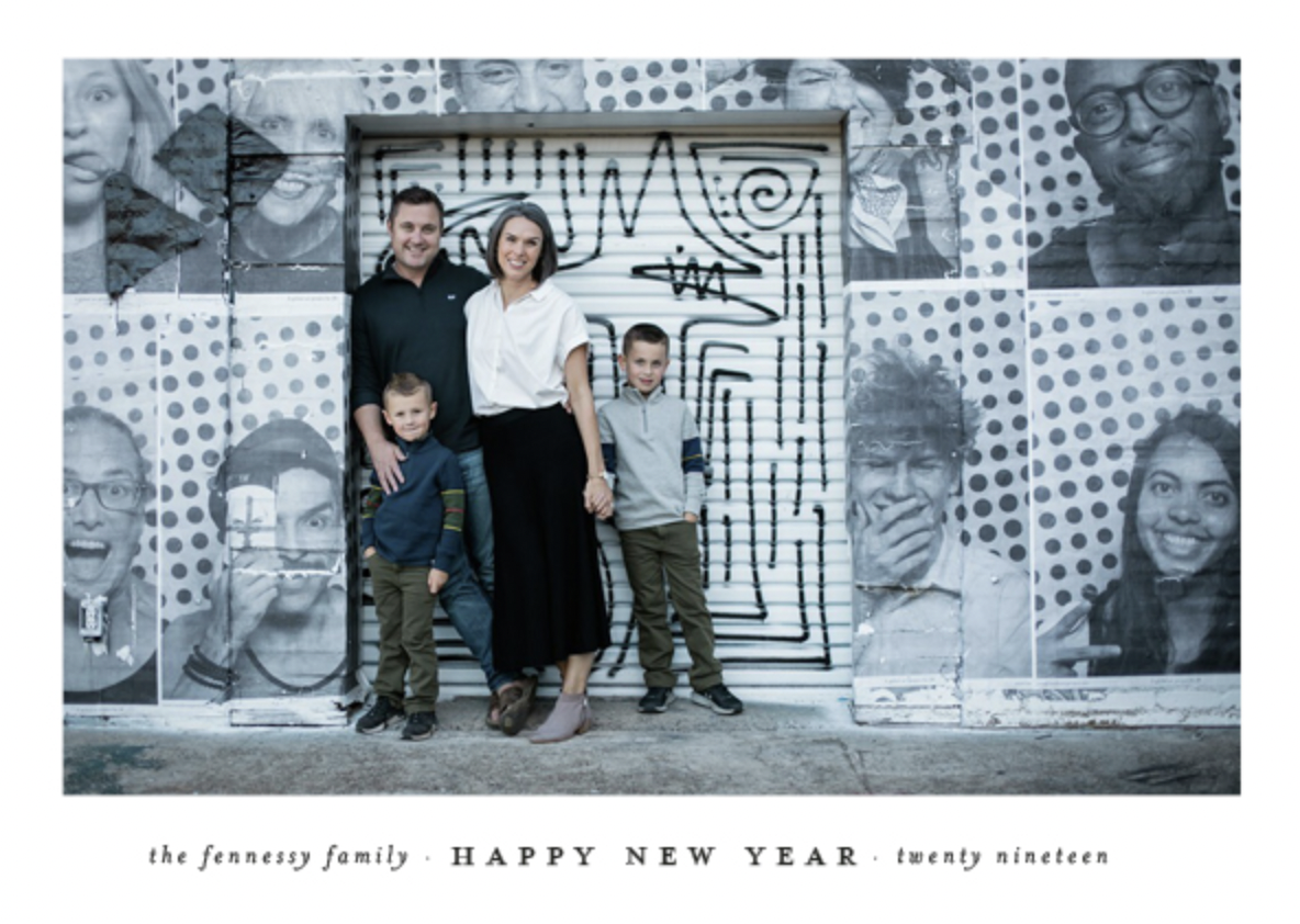 a family of four standing in front of a mural of photos.