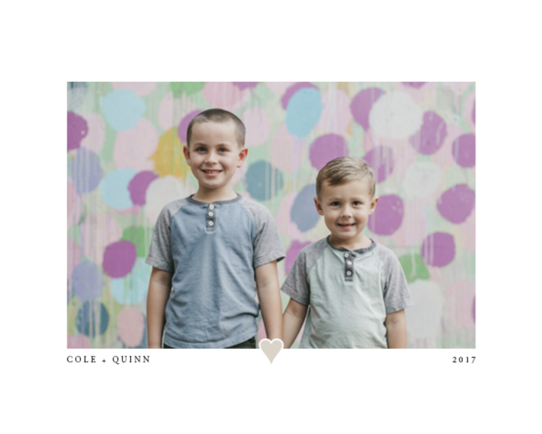 Two little boys standing together in front of a dotted background.