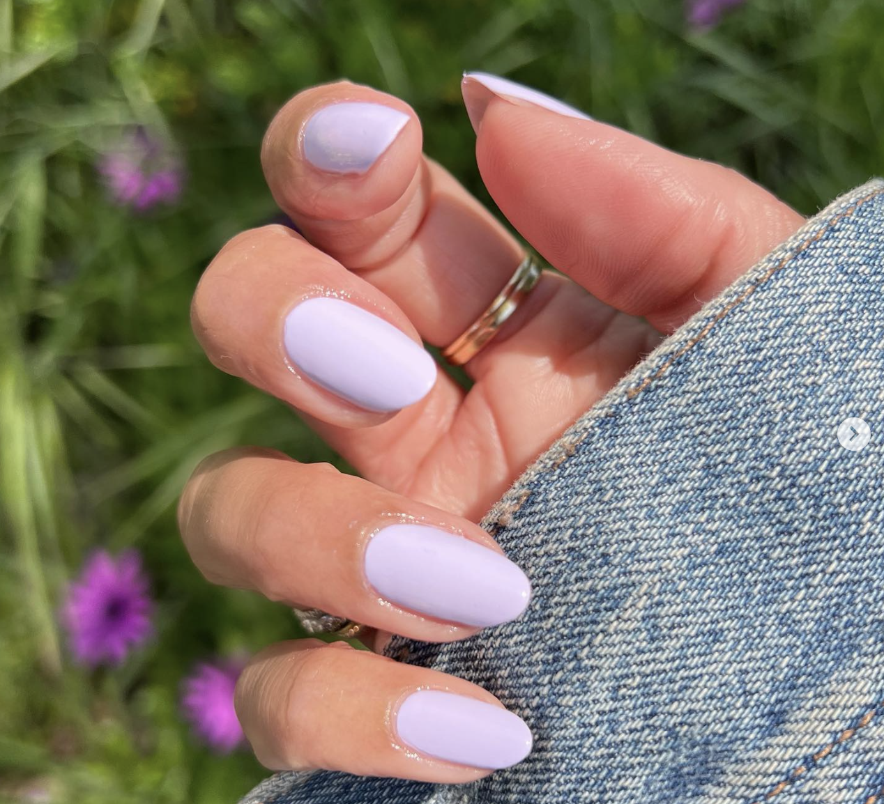 An close up of a hand with lavender colored painted nails.