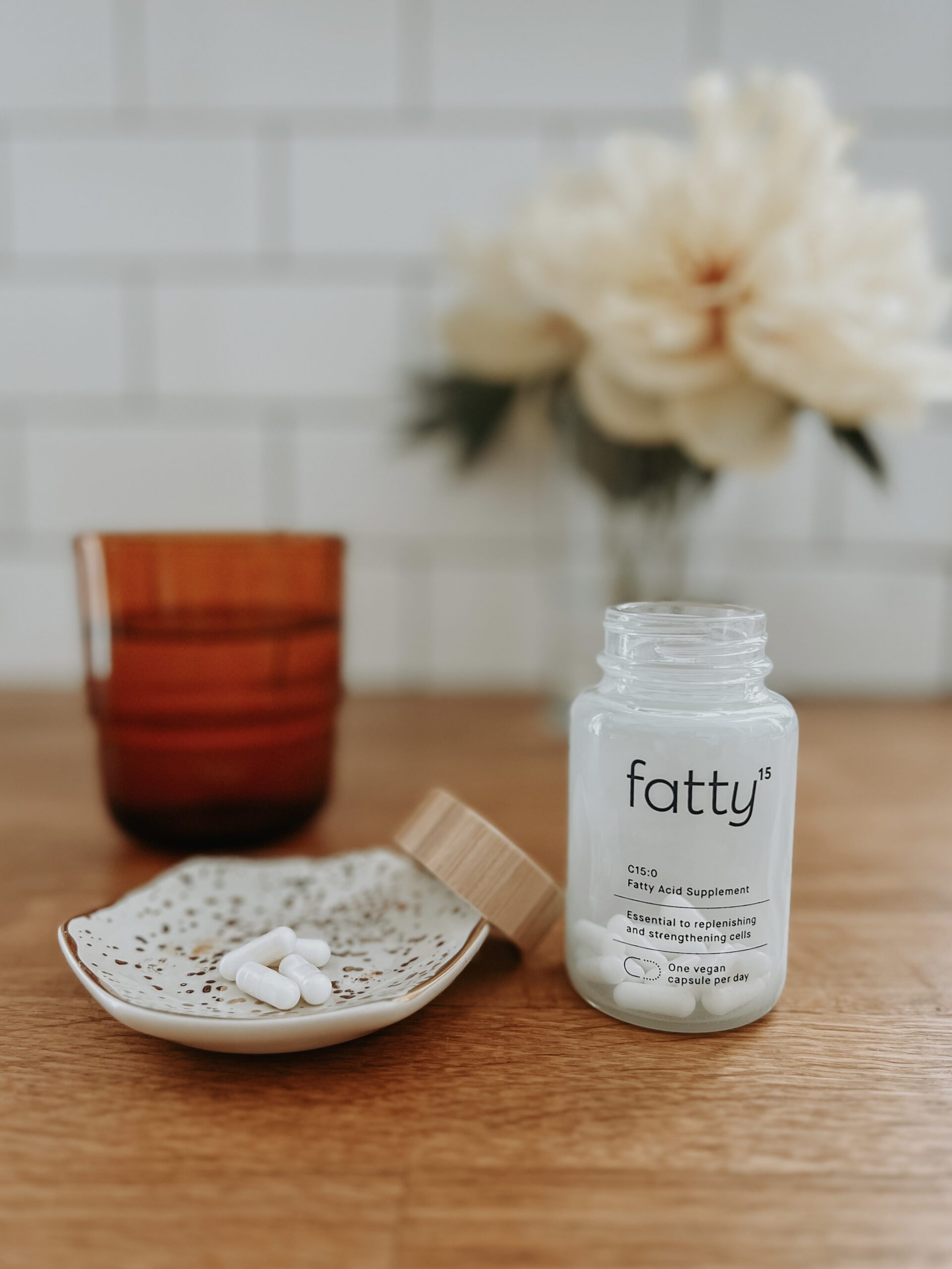 A bottle of fatty15 sits next to a small bowl of capsules.