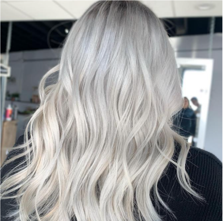 The back view of a woman with long wavy gray hair.