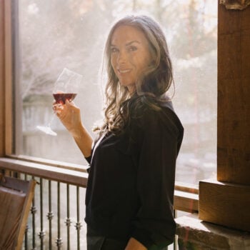 A woman holds up a glass of red wine.
