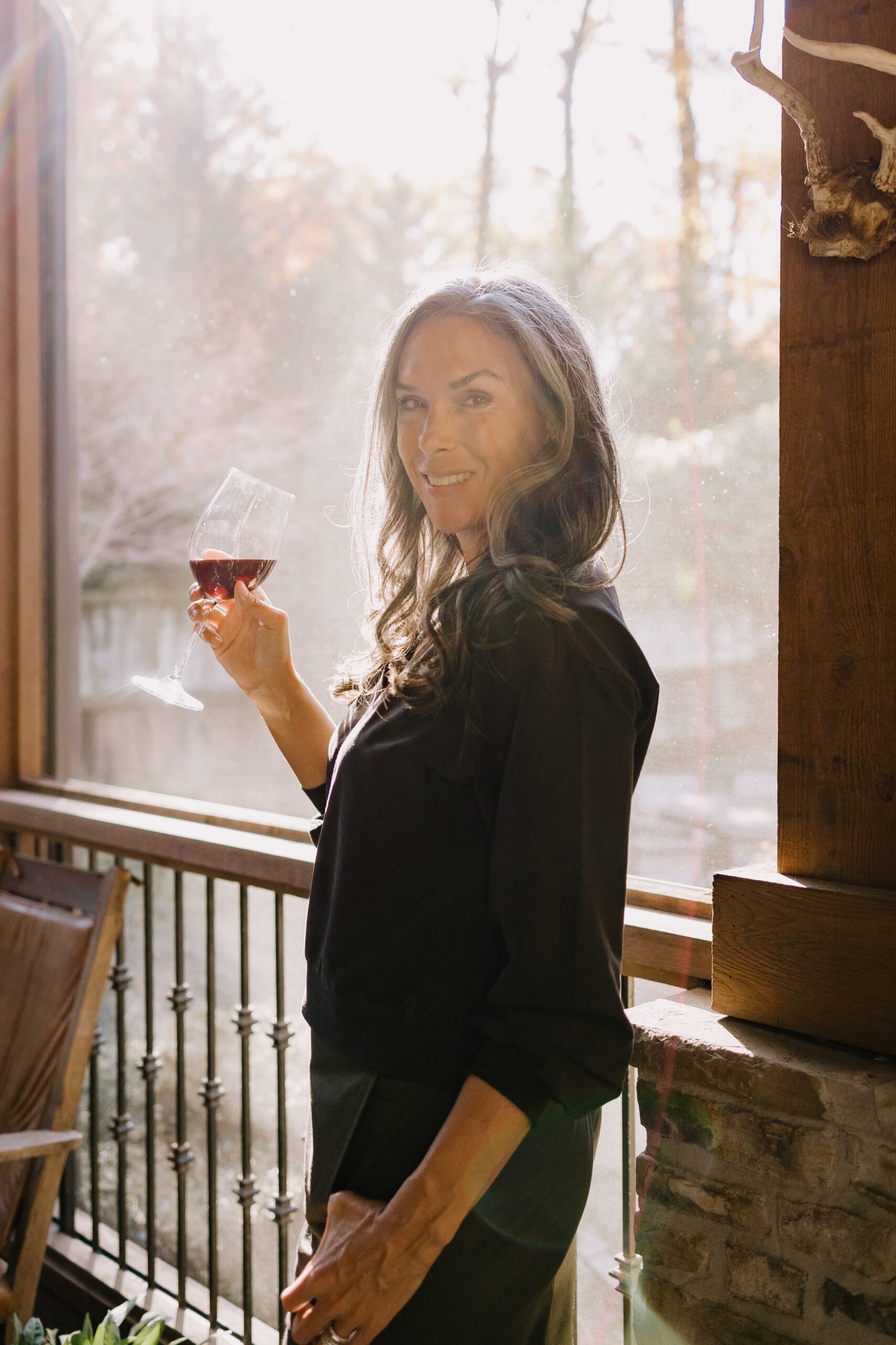 A woman holds up a glass of red wine.