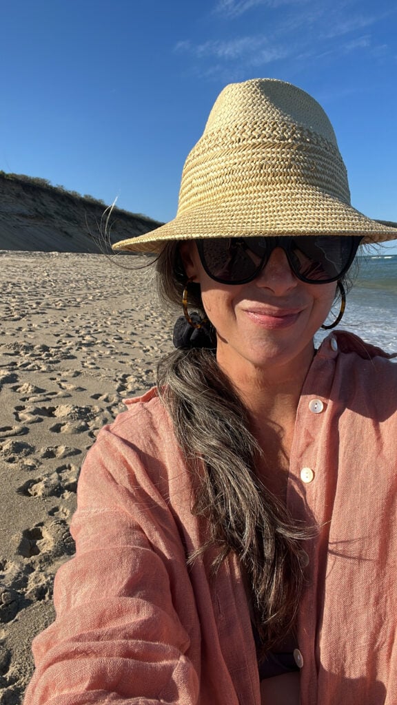 A woman on the beach in a linen coverup.