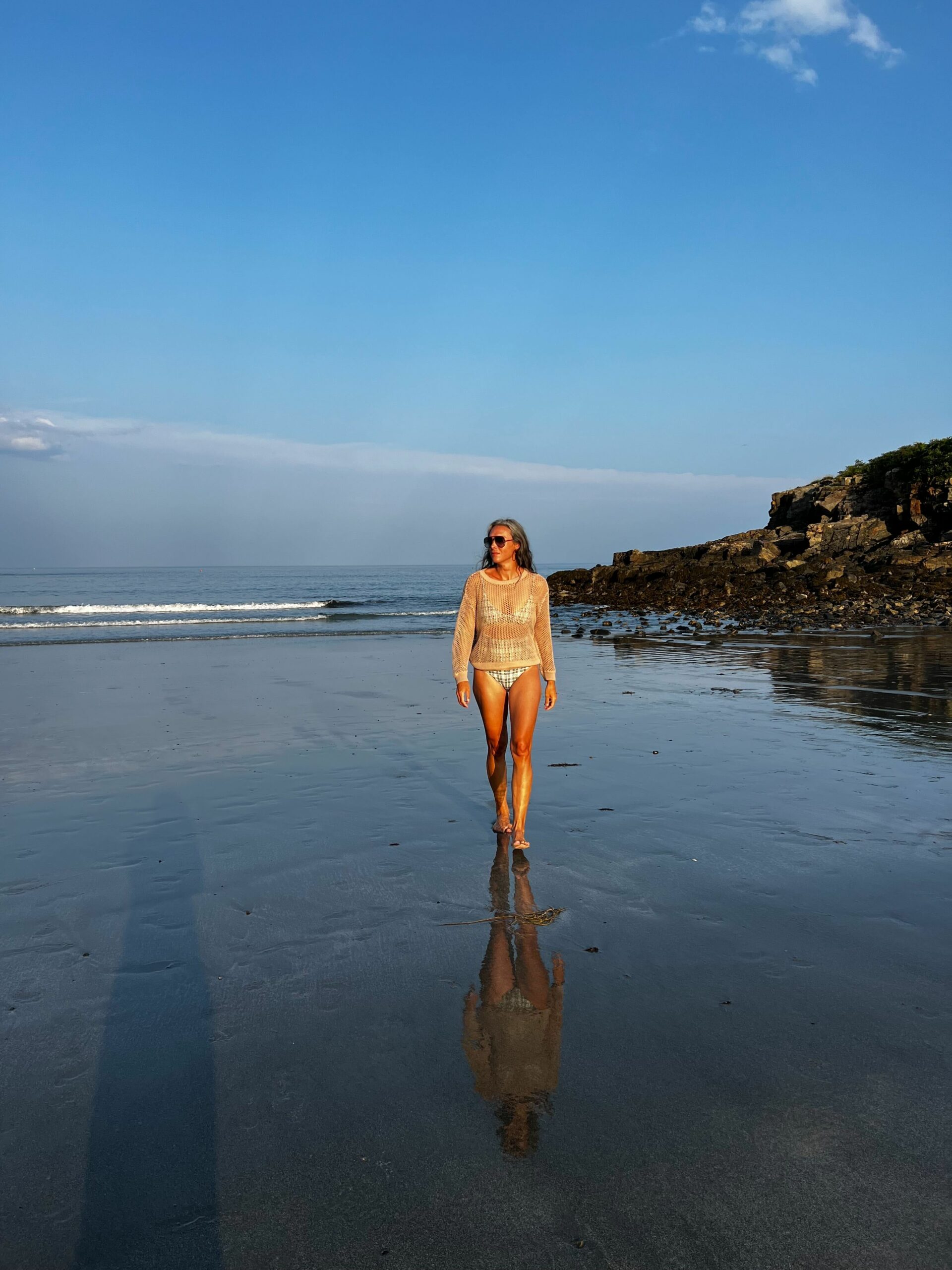 A woman walks on the beach in a sustainable coverup.