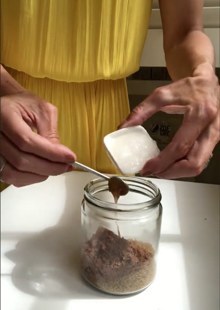 A woman mixing in coconut oil to a body polish recipe.