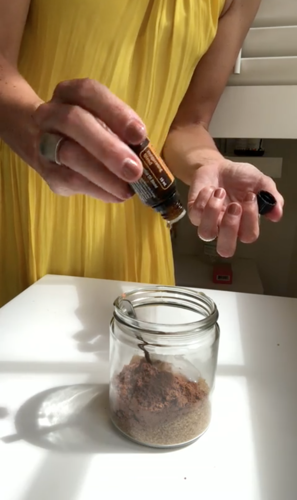 A woman mixes in essential oils into a body polish recipe.