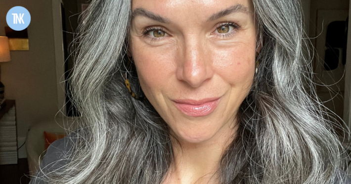 A close up of a woman with long wavy gray hair.