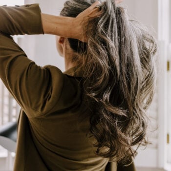 A woman pulling up her long hair.