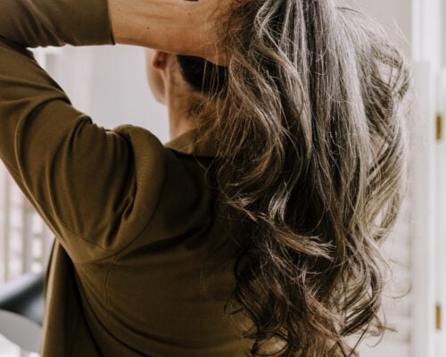 A woman pulling up her long hair.