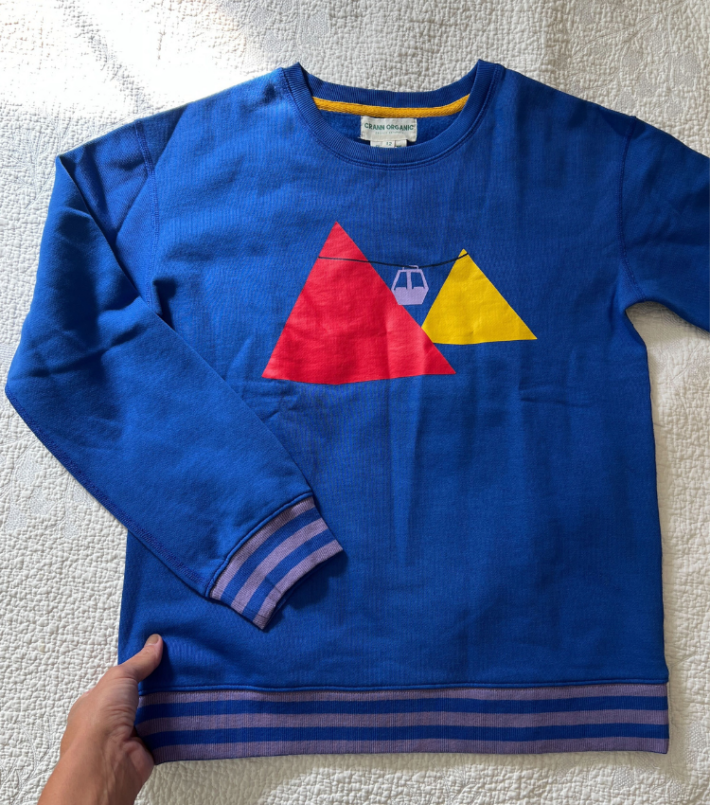 A blue sweatshirt with stripes on the hems. 