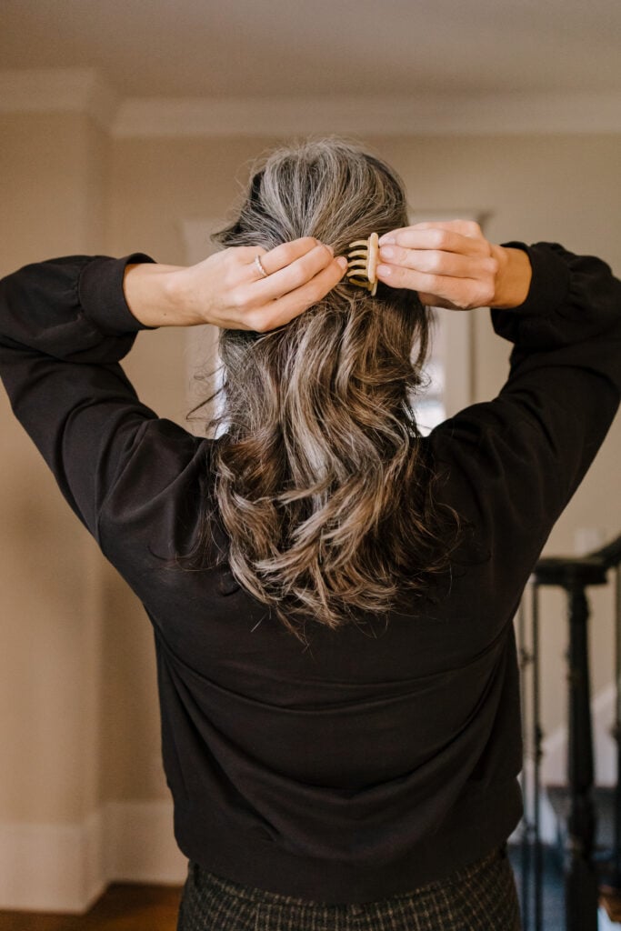 A woman stylers her hair with a claw clip.