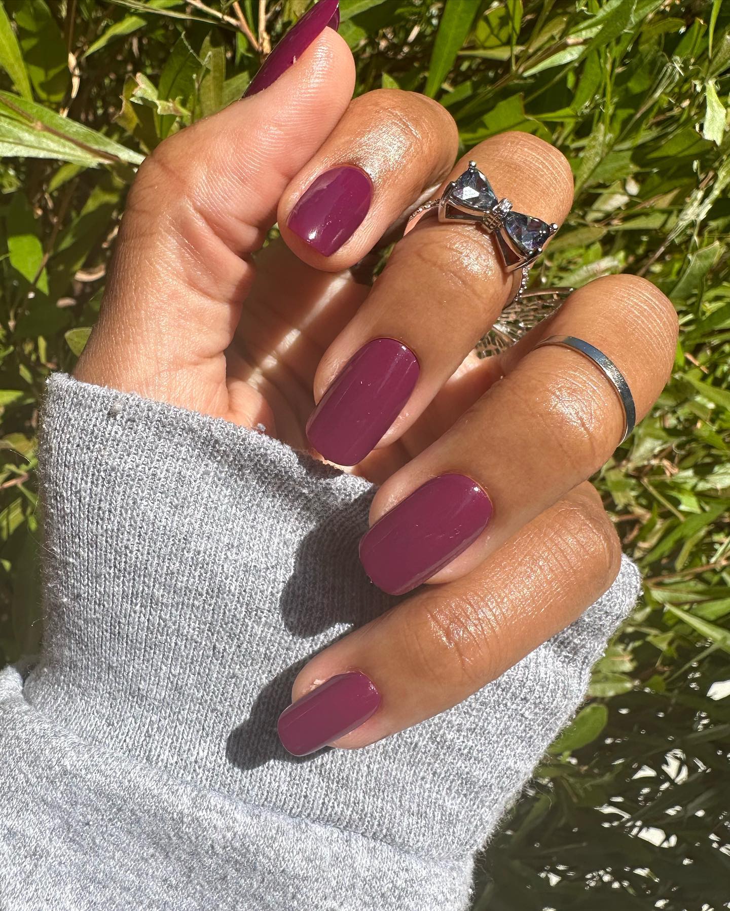 A close up of a hand with plum nail polish on the nails.