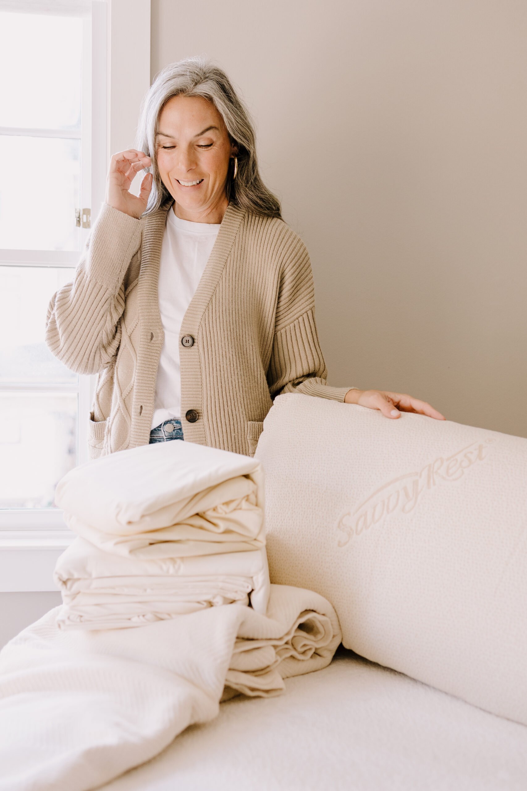 A woman stands with a bedding bundle from Savvy Rest. 
