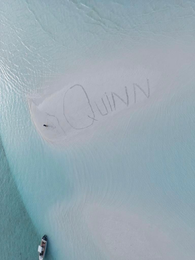 Quinn written in the sand in the ocean. 