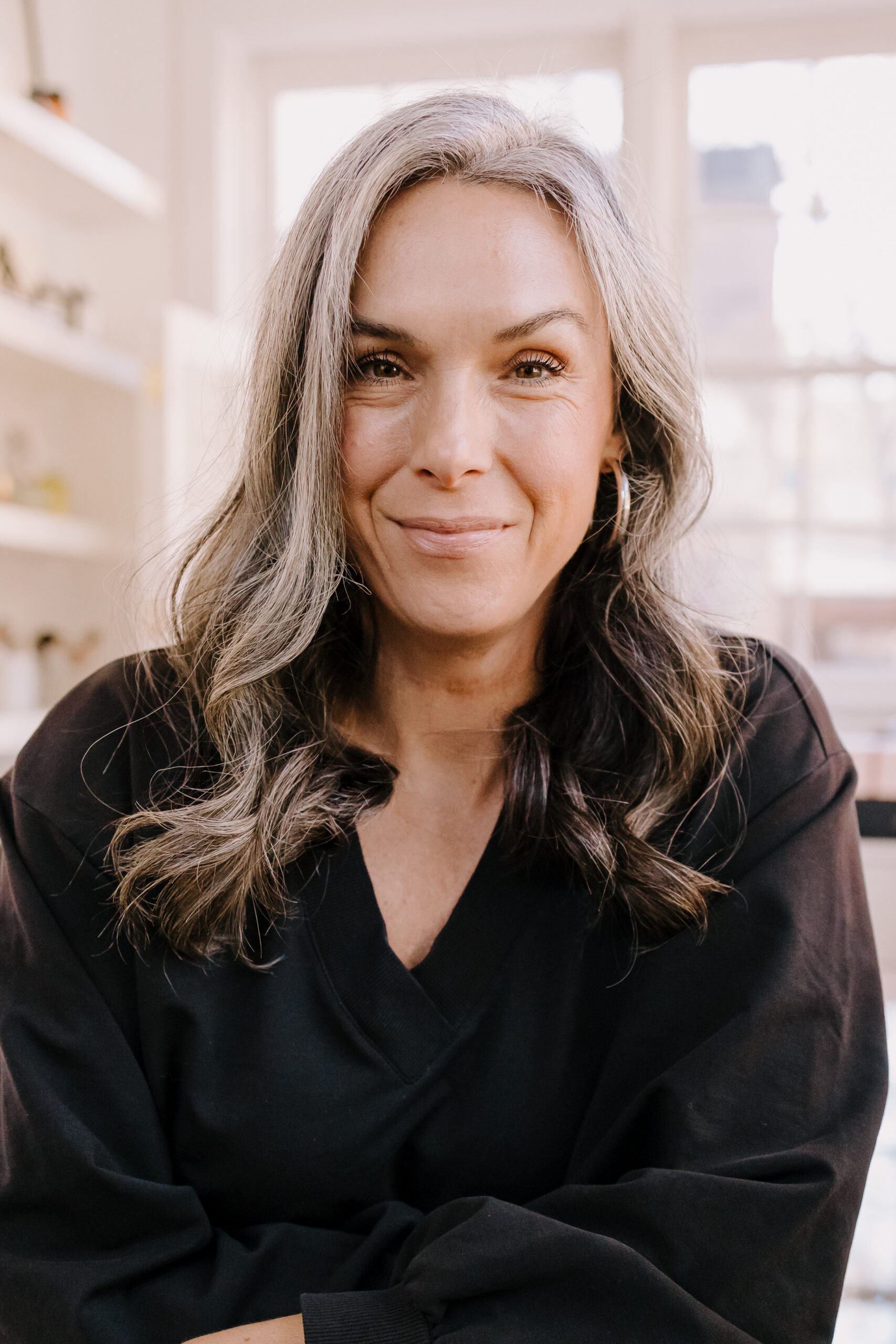 A headshot of a woman with medium length gray hair.