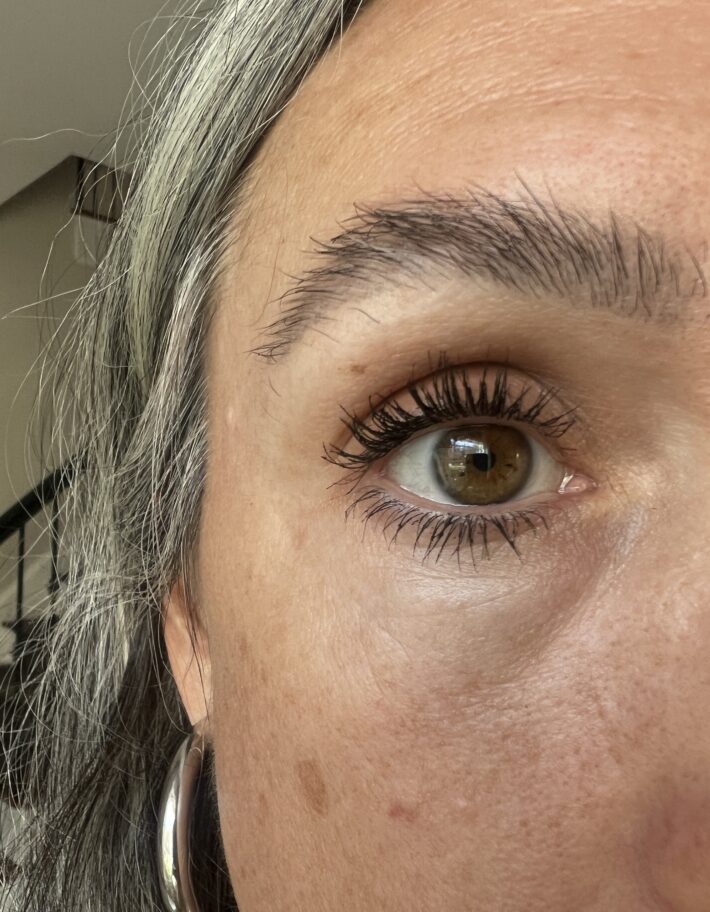 A close up image of Kosas mascara on a woman's eye lashes.