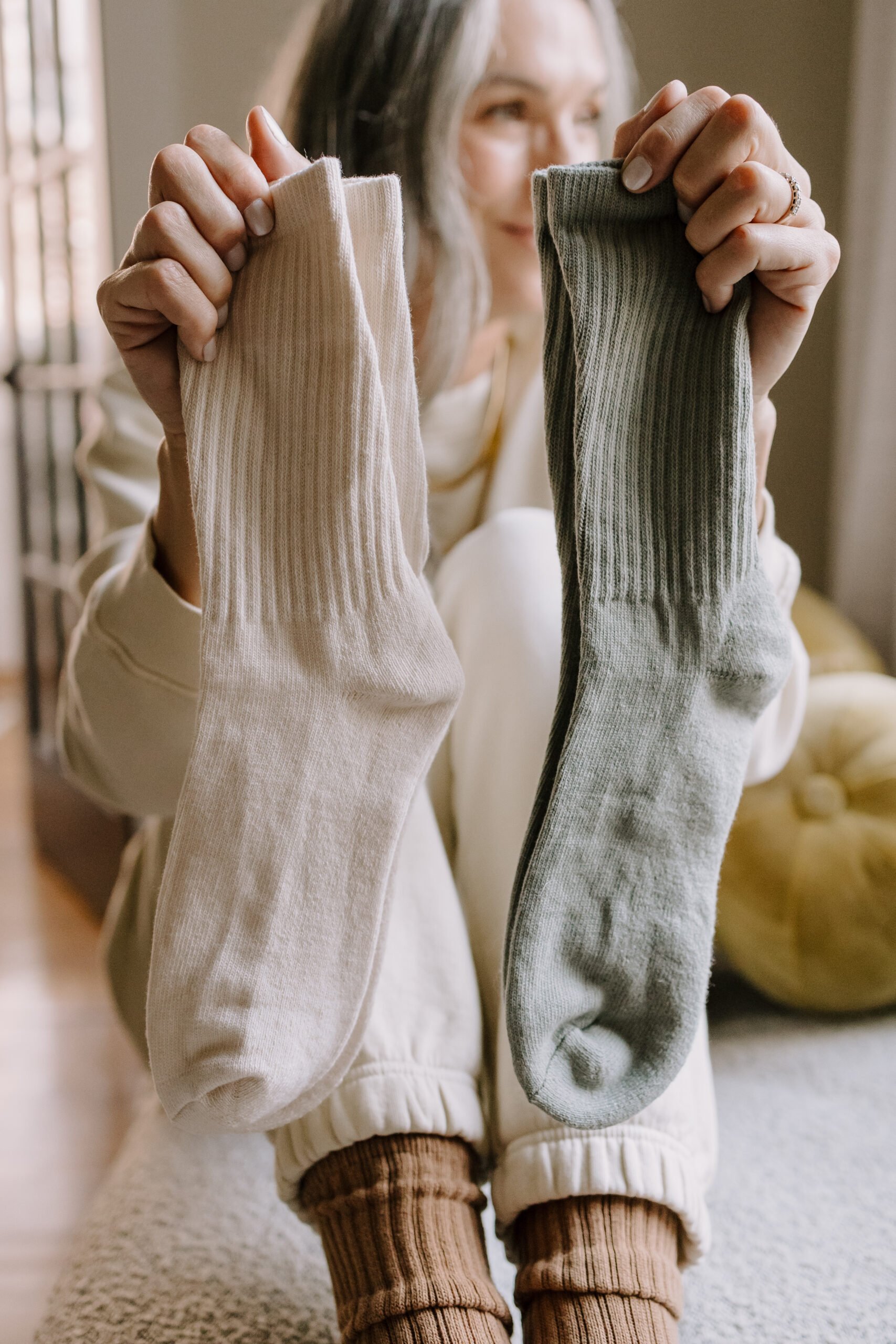 A woman holding up two pairs of socks.