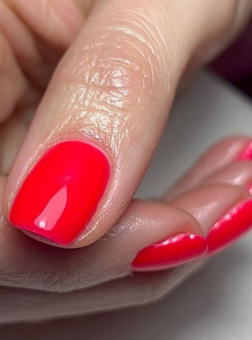 A close up of fingernails painted bright red.