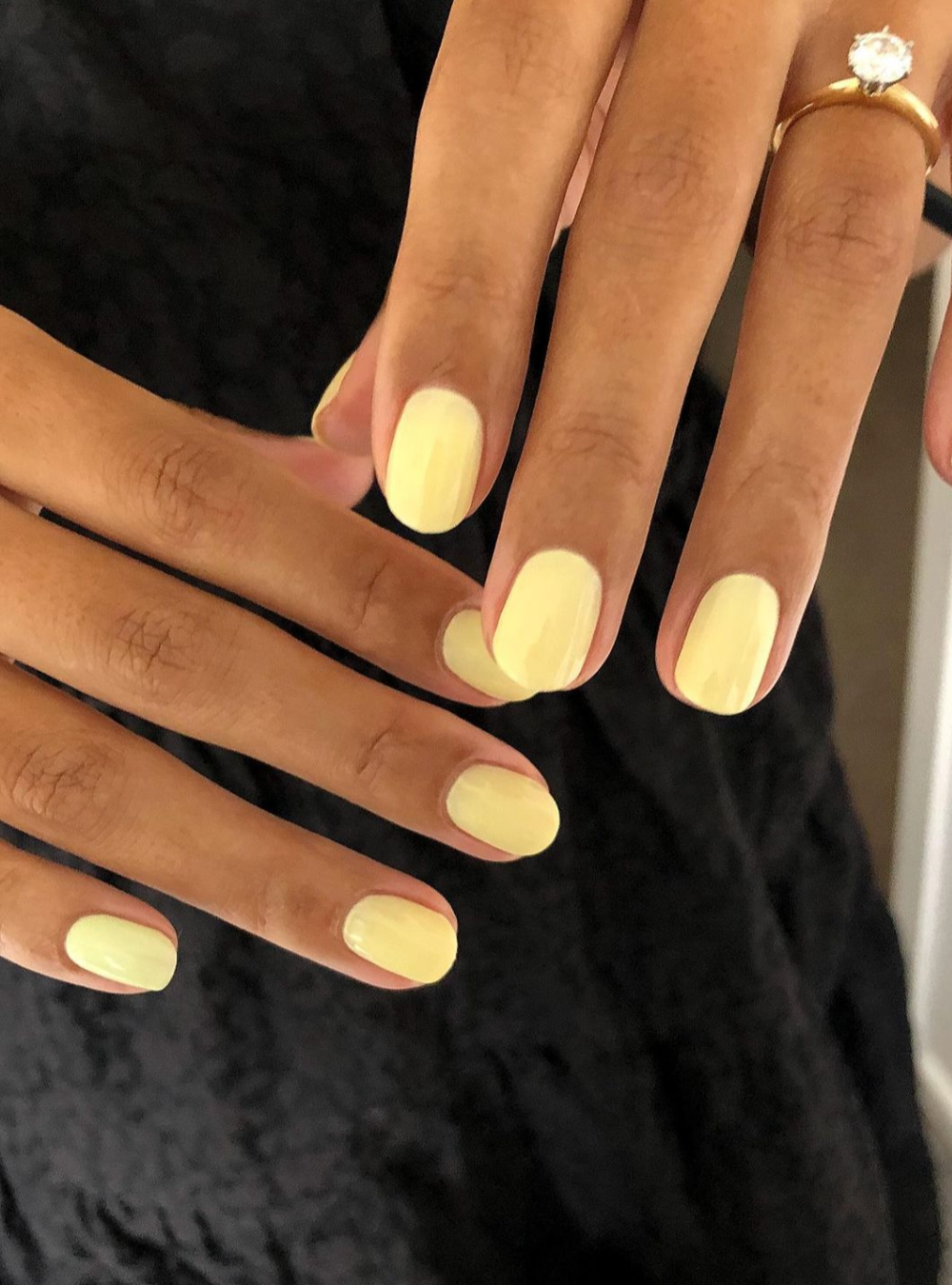 A close up of a hand with light yellow nail polish. 