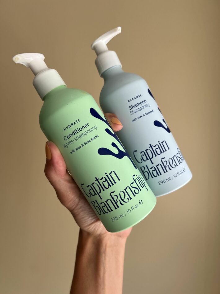 A hand holding up Captain Blankenship shampoo and conditioner.