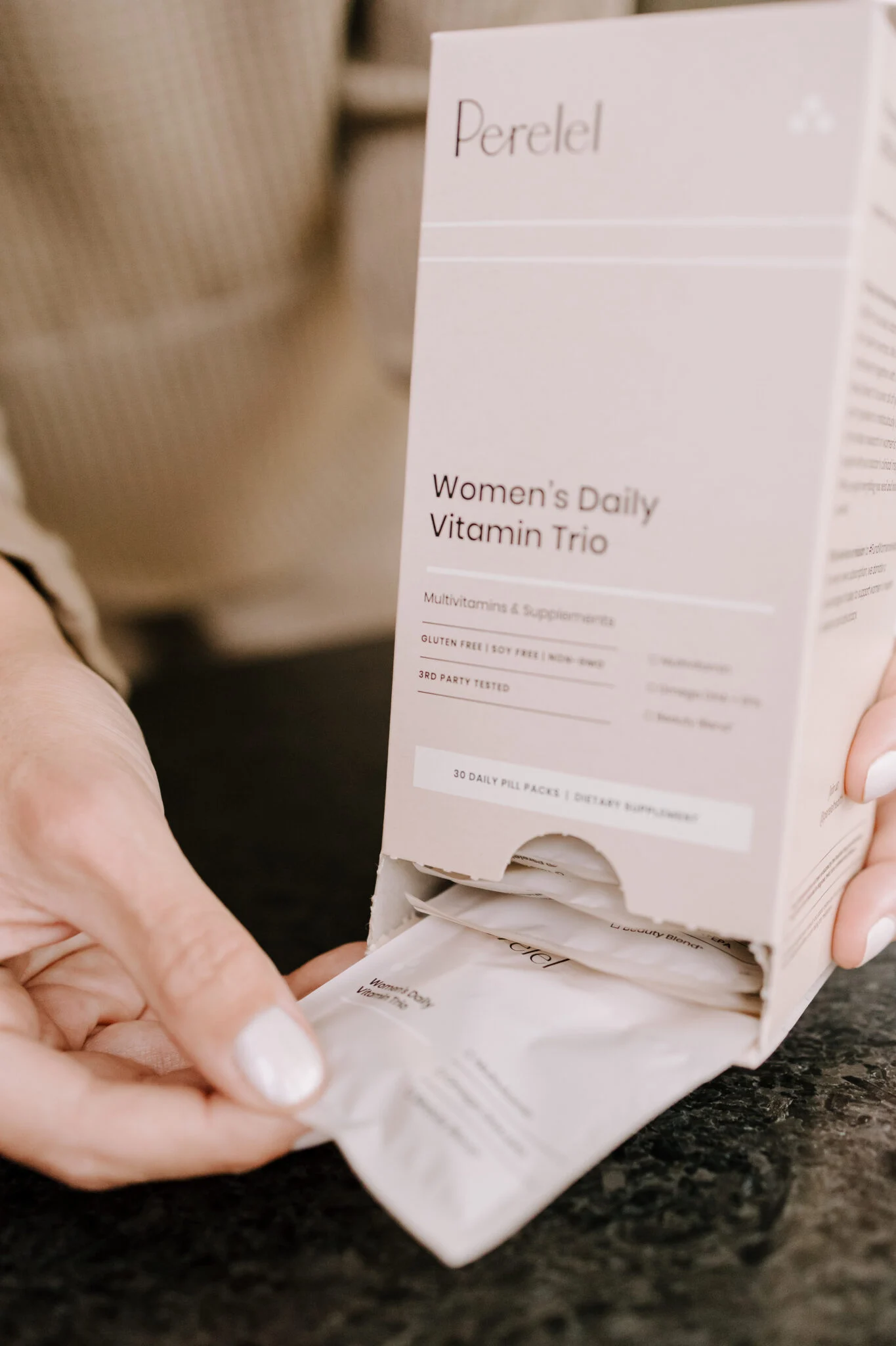 A woman holding up a Daily Vitamin Trio in packaging.