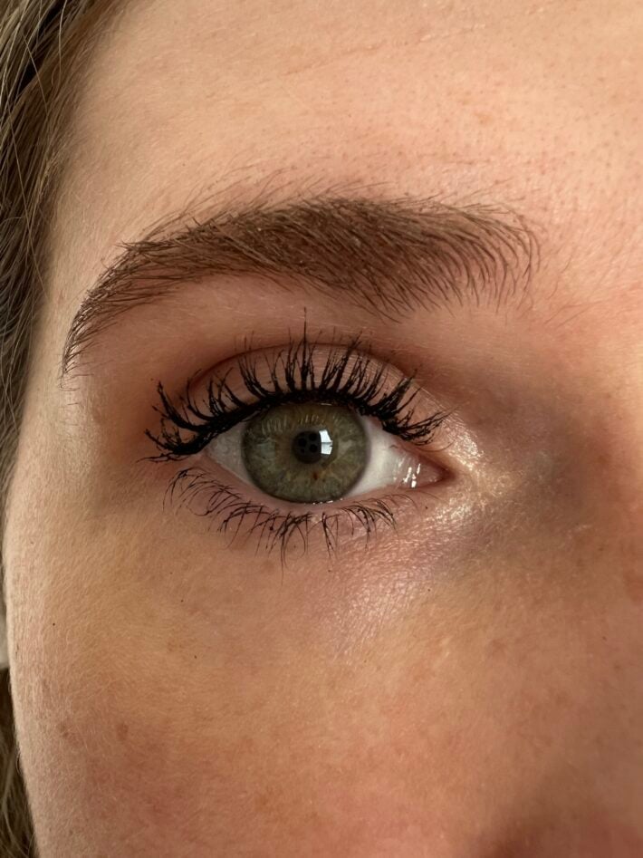 A close up of a woman's eye while she is wearing W3LL People's Expressionist Volumizing Mascara.