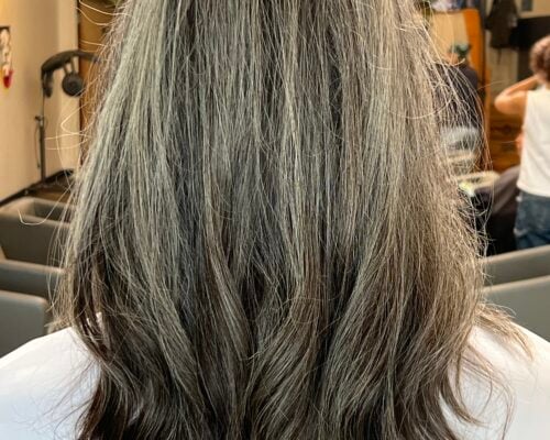 The backside of a woman's head after getting clear hair glaze on her gray hair.
