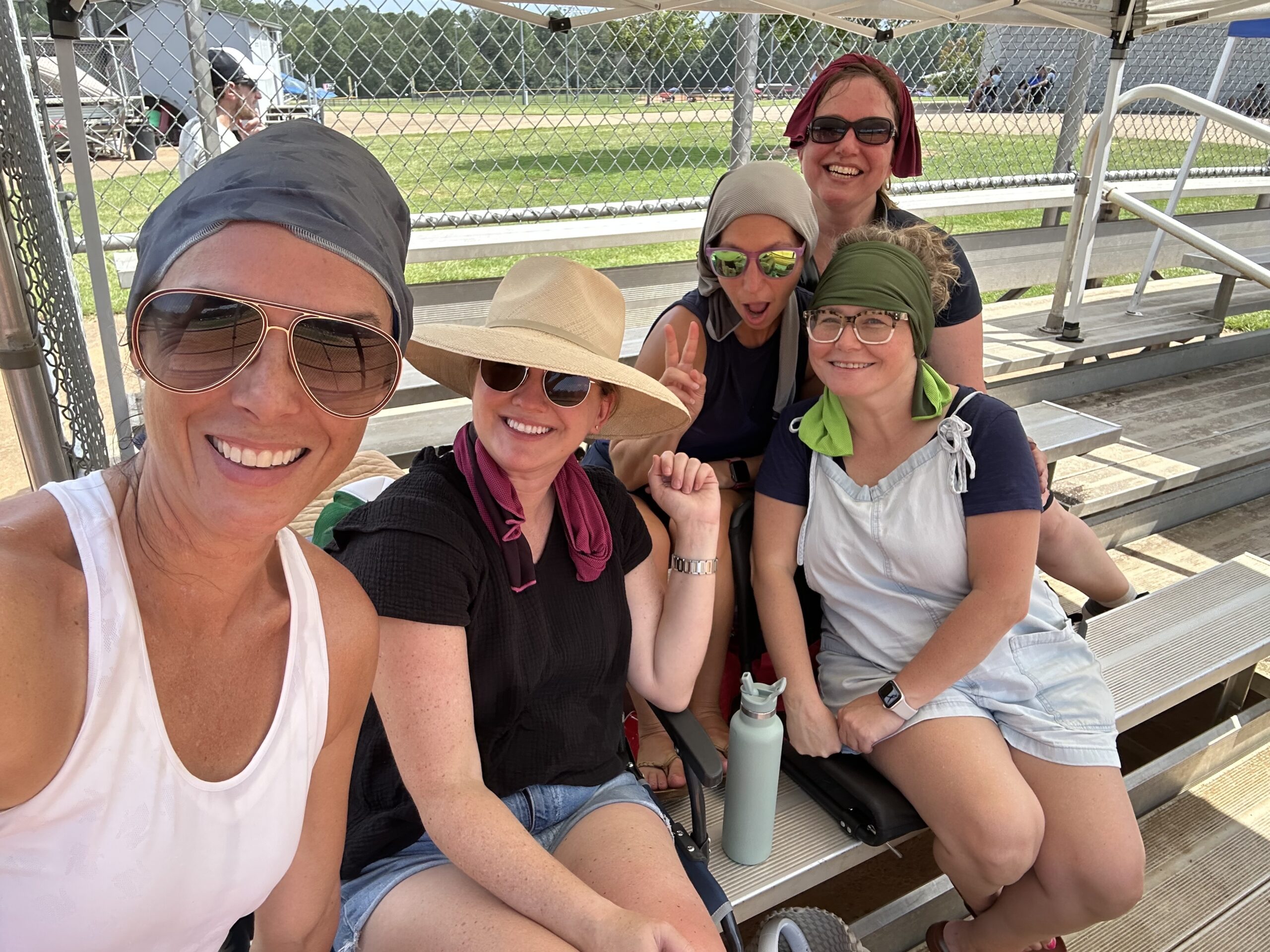 A group of moms sit on the bleachers.