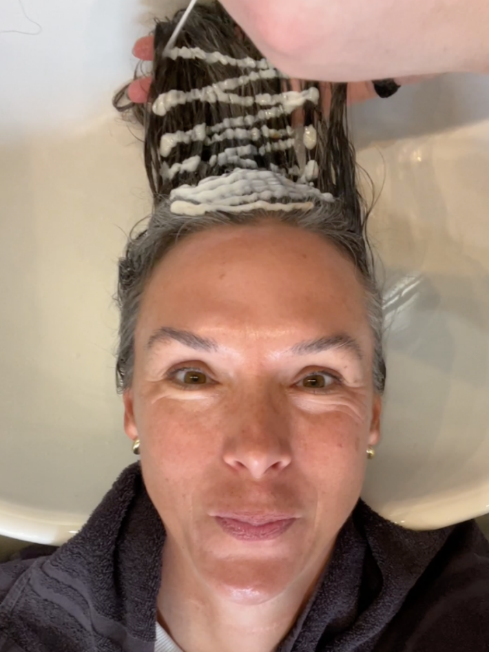 A woman getting a clear glaze on her gray hair. The length of her hair was coated with hair glaze during the process.