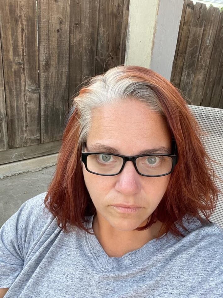 A selfie of a woman going from red hair to gray.